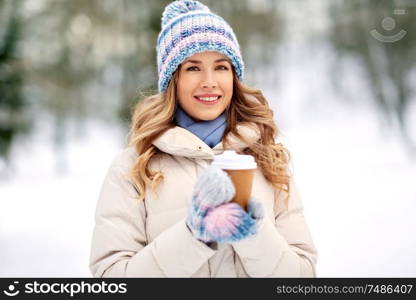 people, hot drinks and leisure concept - happy woman drinking takeaway coffee outdoors in winter. happy woman drinking coffee outdoors in winter