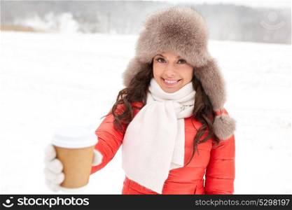 people, hot drinks and leisure concept - happy woman in winter fur with coffee cup hat outdoors. happy woman in winter fur hat with coffee outdoors