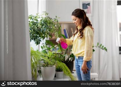 people, housekeeping and plants care concept - asian woman spraying houseplant with water sprayer at home. asian woman spraying houseplant with water at home