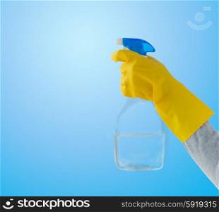 people, housework and housekeeping concept - close up of hand with cleanser spraying over blue background