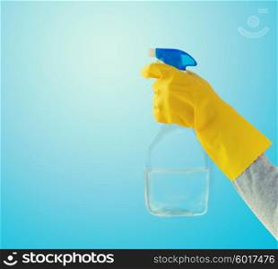 people, housework and housekeeping concept - close up of hand with cleanser spraying over blue background