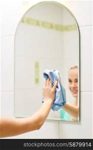 people, housework and housekeeping concept - close up of happy woman cleaning mirror with rag at home