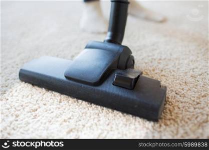 people, housework and housekeeping concept - close up of vacuum cleaner nozzle cleaning carpet at home