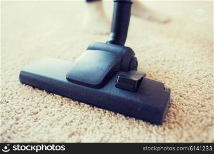 people, housework and housekeeping concept - close up of vacuum cleaner nozzle cleaning carpet at home