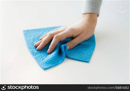 people, housework and housekeeping concept - close up of woman hand cleaning table surface with cloth at home