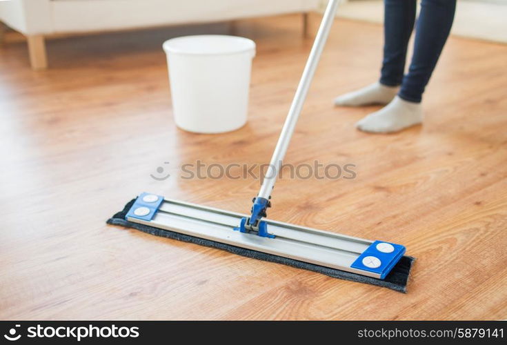 people, housework and housekeeping concept - close up of woman legs with mop cleaning floor at home