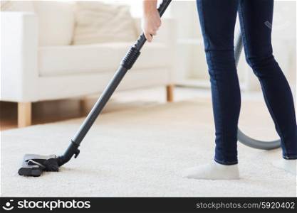 people, housework and housekeeping concept - close up of woman with legs vacuum cleaner cleaning carpet at home