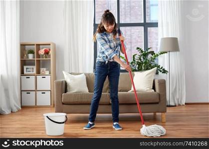 people, housework and housekeeping concept - happy asian woman with mop and bucket cleaning floor at home. happy asian woman with mop cleaning floor at home