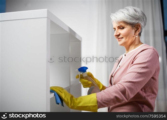 people, housework and housekeeping concept - happy senior woman cleaning rack with detergent and rag at home. senior woman cleaning rack with detergent at home