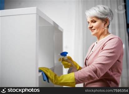 people, housework and housekeeping concept - happy senior woman cleaning rack with detergent and rag at home. senior woman cleaning rack with detergent at home