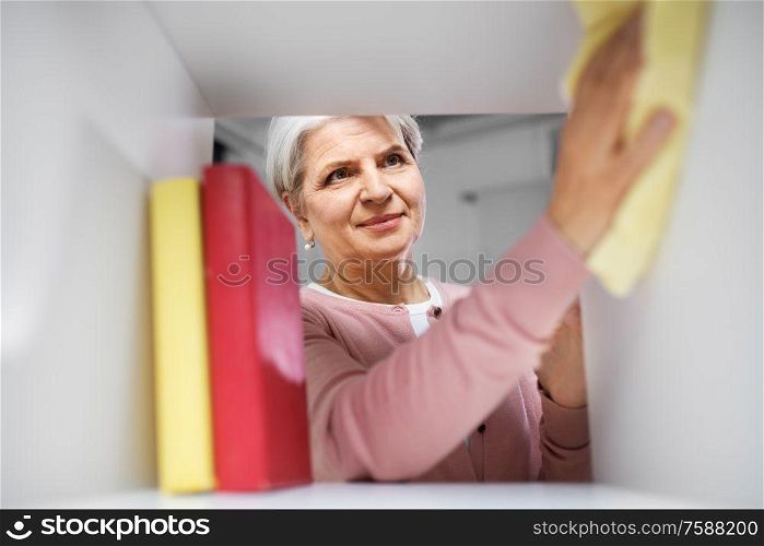 people, housework and housekeeping concept - happy senior woman with dusting cloth cleaning rack at home. happy senior woman with cloth dusting rack at home