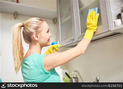 people, housework and housekeeping concept - happy woman cleaning cabinet with rag and cleanser at home kitchen