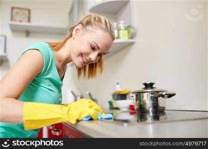 people, housework and housekeeping concept - happy woman cleaning cooker at home kitchen. happy woman cleaning cooker at home kitchen