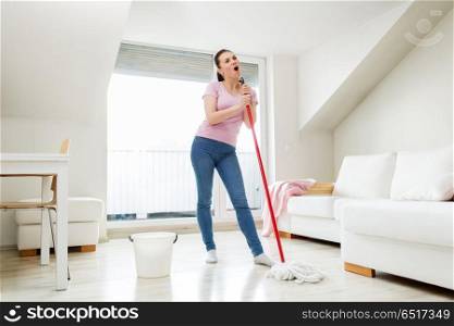 people, housework and housekeeping concept - happy woman or housewife with mop cleaning floor and singing at home. woman or housewife with mop cleaning floor at home. woman or housewife with mop cleaning floor at home