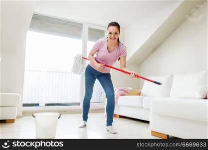people, housework and housekeeping concept - happy woman or housewife with mop cleaning floor and having fun at home. woman or housewife with mop cleaning floor at home. woman or housewife with mop cleaning floor at home