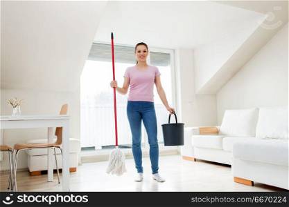 people, housework and housekeeping concept - happy woman or housewife with mop cleaning floor and dancing at home. woman or housewife with mop cleaning floor at home. woman or housewife with mop cleaning floor at home