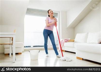 people, housework and housekeeping concept - happy woman or housewife with mop cleaning floor and singing at home. woman or housewife with mop cleaning floor at home. woman or housewife with mop cleaning floor at home