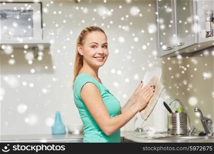 people, housework and housekeeping concept - happy woman wiping dishes at home kitchen over snow effect