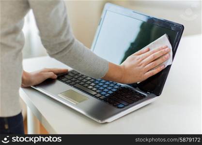 people, housework, electronics and housekeeping concept - close up of woman hands cleaning laptop computer screen with cloth