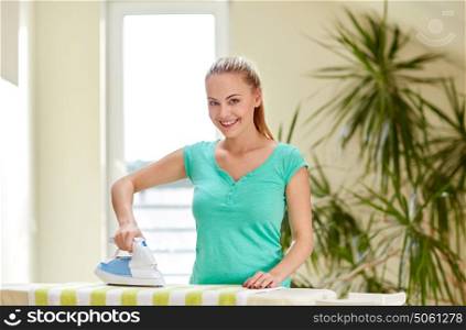 people, housework, laundry and housekeeping concept - happy woman with iron and ironing board at home. happy woman with iron and ironing board at home