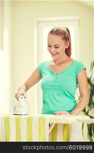 people, housework, laundry and housekeeping concept - happy woman with iron and ironing board at home
