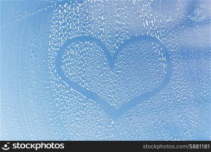 people, housework, love, valentines day and housekeeping concept - close up of heart shape drawing on soapy window glass