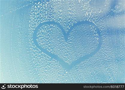 people, housework, love, valentines day and housekeeping concept - close up of heart shape drawing on soapy window glass