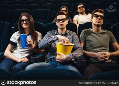 People in 3d glasses with popcorn and drinks watching movie in cinema. Entertainment business. People with popcorn watching movie in cinema