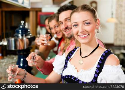 People in Bavarian Tracht drinking hard liquor in a pub and have fun