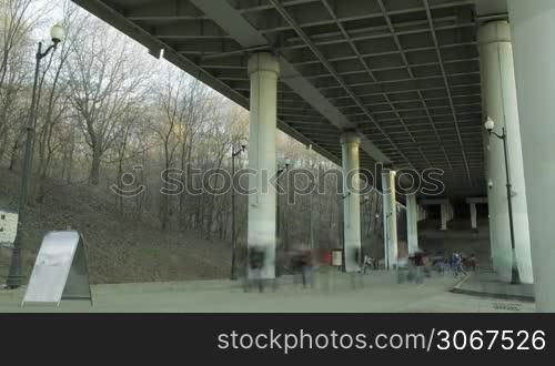 People in blur walking under the metro bridge in Moscow. Time lapse.