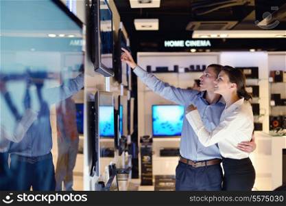 people in consumer electronics retail store looking at latest laptop, television and photo camera to buy