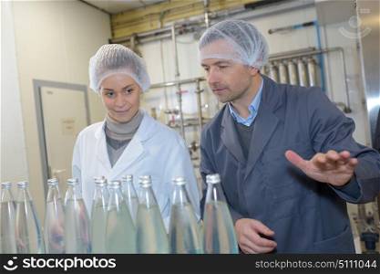 People in factory looking at glass bottles