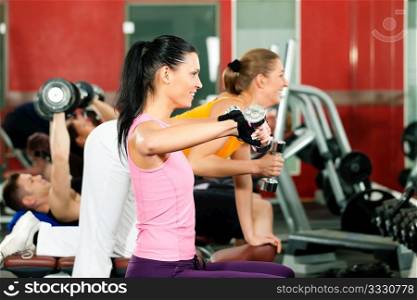 People in gym or fitness club exercising with weights together