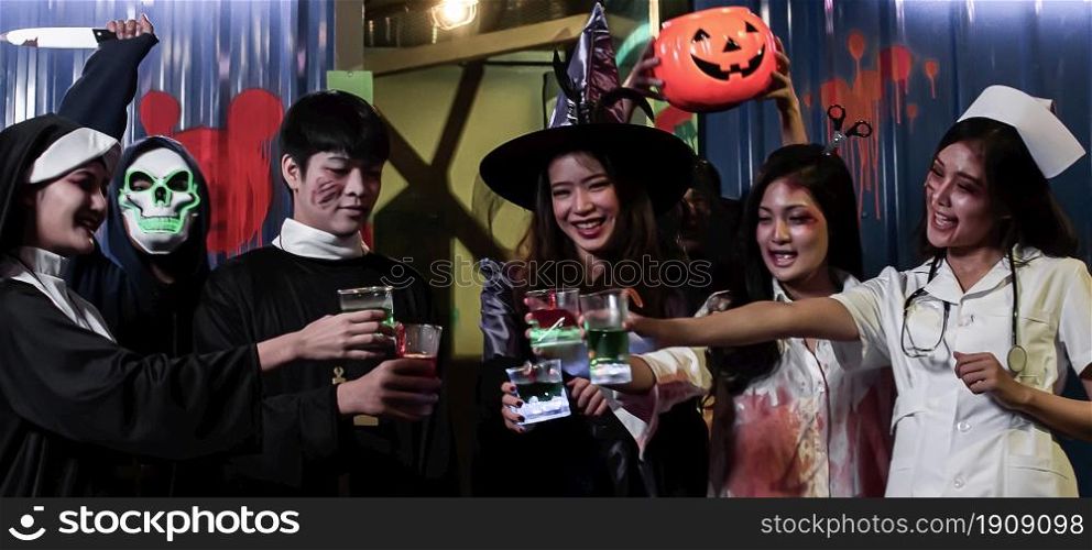 People in halloween costume dancing, having fun and drinking together in party at night