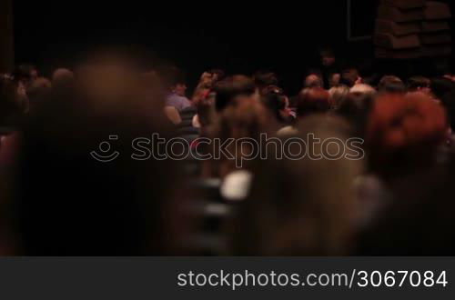 People in the theatre. Pan shot from the back.