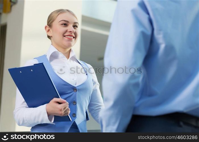 People indoors having talk. Businesswoman and man in modern interior holding document case and talking to her colleague