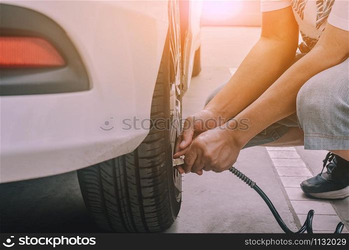 People inflating the tires of car parked