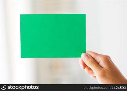 people, information, advertisement and ecology concept - close up of hand holding green paper card
