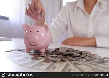 people inserting coin in Piggybank with coins and money over the desk 