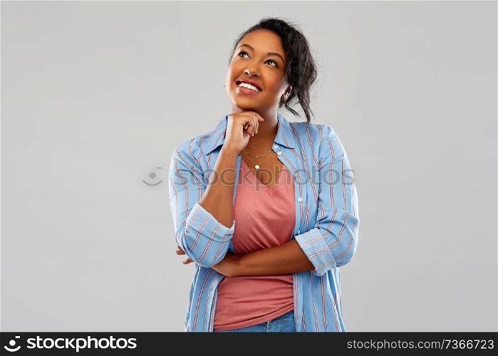 people, inspiration and dream concept - happy african american young woman dreaming over grey background. happy african american woman dreaming