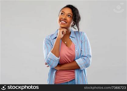 people, inspiration and dream concept - happy african american young woman dreaming over grey background. happy african american woman dreaming