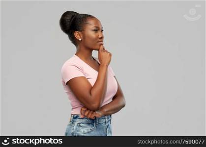 people, inspiration and dream concept - happy african american young woman thinking over grey background. african american woman thinking or dreaming
