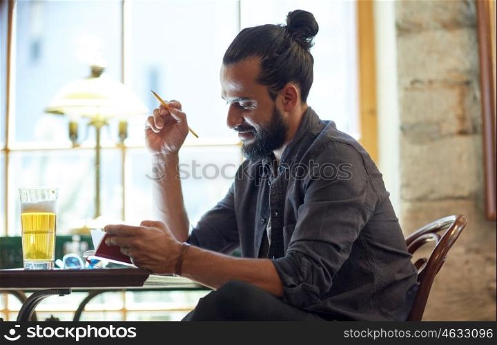 people, inspiration, freelance and leisure concept - close up of man with beer writing to notebook at bar or pub