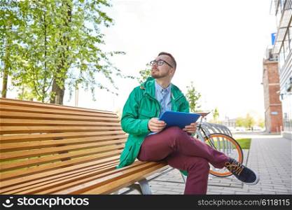 people, inspiration, technology and lifestyle - happy young hipster man with tablet pc computer sitting and thinking on bench in city