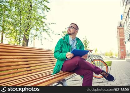 people, inspiration, technology and lifestyle - happy young hipster man with tablet pc computer sitting and thinking on bench in city