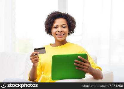 people, internet bank, online shopping, technology and e-money concept - happy african american young woman sitting on sofa with tablet pc computer and credit card at home