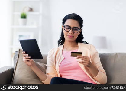 people, internet bank, online shopping, technology and e-money concept - happy woman with tablet pc and credit card at home. happy woman with tablet pc and credit card at home