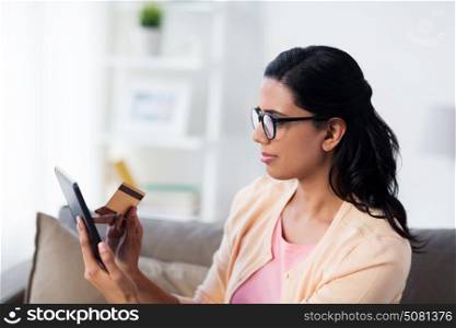 people, internet bank, online shopping, technology and e-money concept - happy woman with tablet pc and credit card at home. happy woman with tablet pc and credit card at home