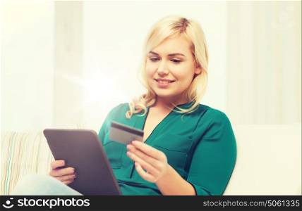 people, internet bank, online shopping, technology and e-money concept - happy young woman sitting on sofa with tablet pc computer and credit card at home. happy woman with tablet pc and credit card