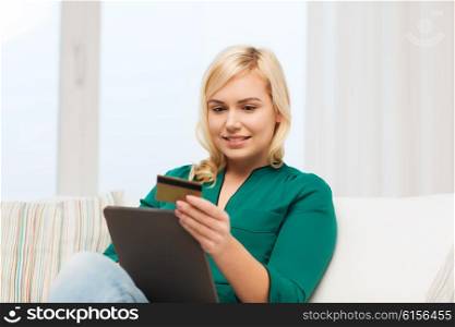 people, internet bank, online shopping, technology and e-money concept - happy young woman sitting on sofa with tablet pc computer and credit card at home